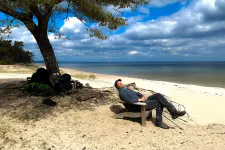 Man resting in a chair on a beach under a tree