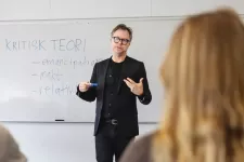 A teacher, dressed in black, is teaching in critical theory. Photo.