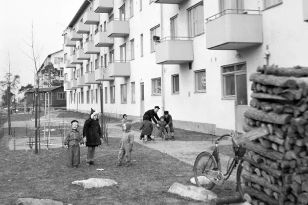 Kids standing outside an apartment building. Black and white photo.