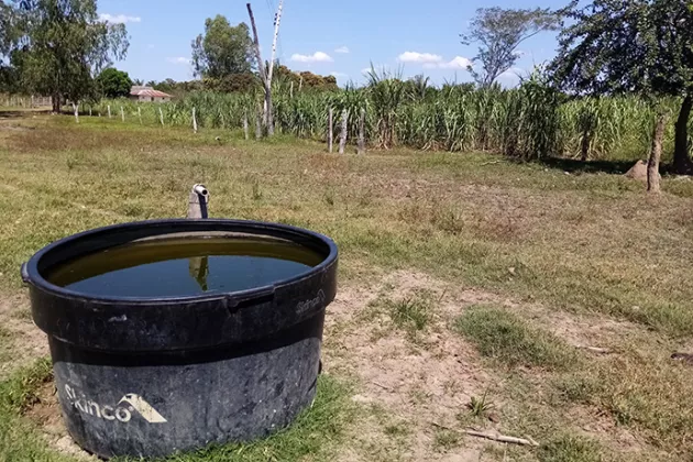 Water tank in the front with a farm lot in the background.