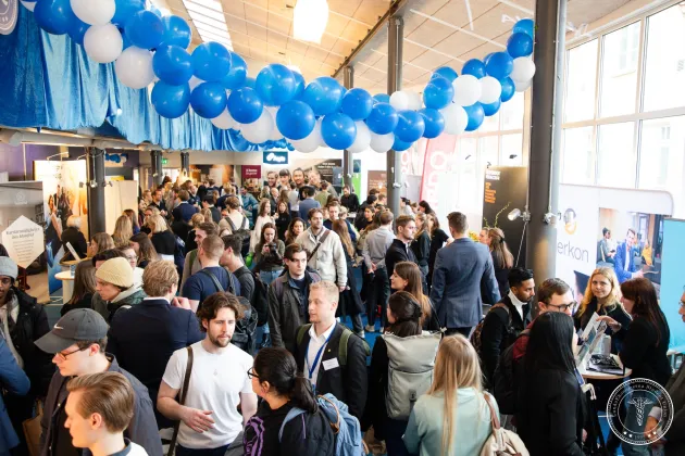 Många människor i mässliknande miljö. Foto. 