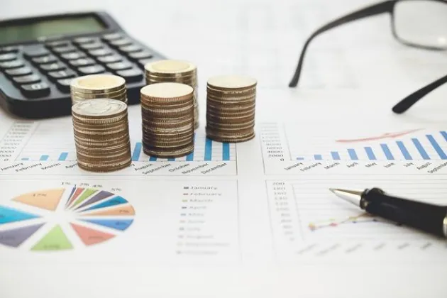 Pile of coins and paper with charts. Photo.
