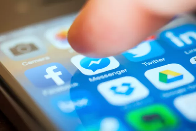 finger hovering over a mobile screen showing social media apps