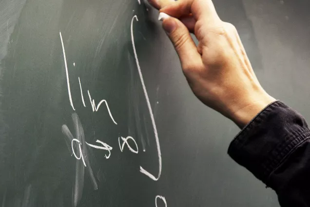A hand in front of a blackboard