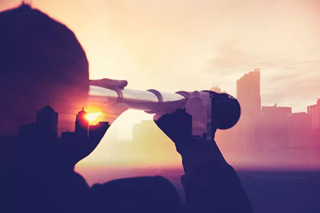 Person looks through and old binocular at a city in the horizon. Photograph.