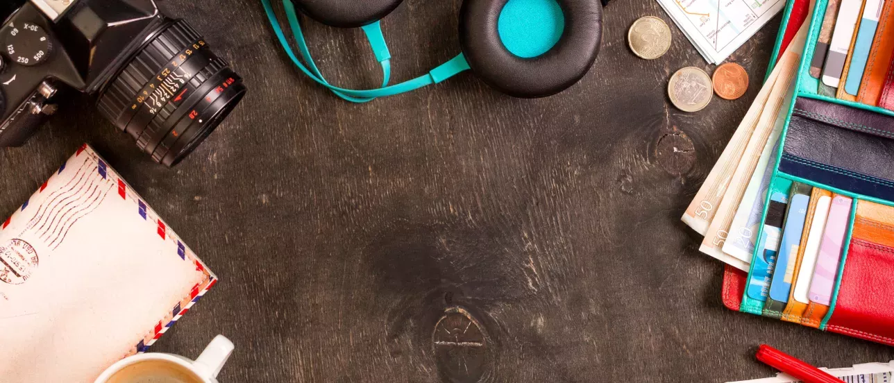 Assortment of traveling items on a table, camera, headphones, wallet, coins envelope. Photo